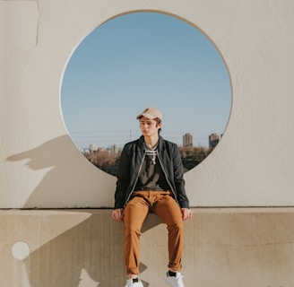 man sitting on gray concrete wall