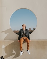 man sitting on gray concrete wall