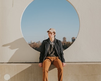 man sitting on gray concrete wall