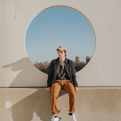 man sitting on gray concrete wall