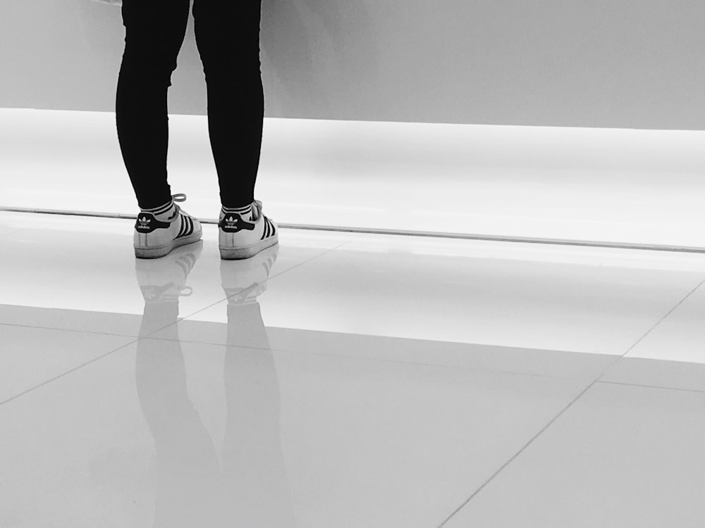 Persona con un par de zapatillas adidas blancas y negras para correr