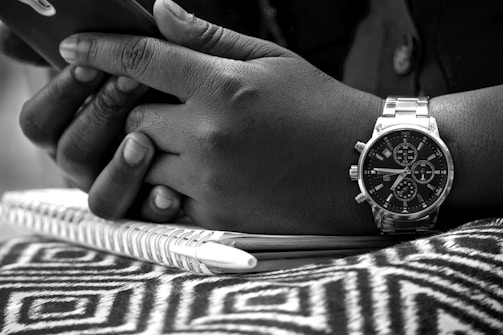 A close-up of hands exchanging ideas over a notebook.