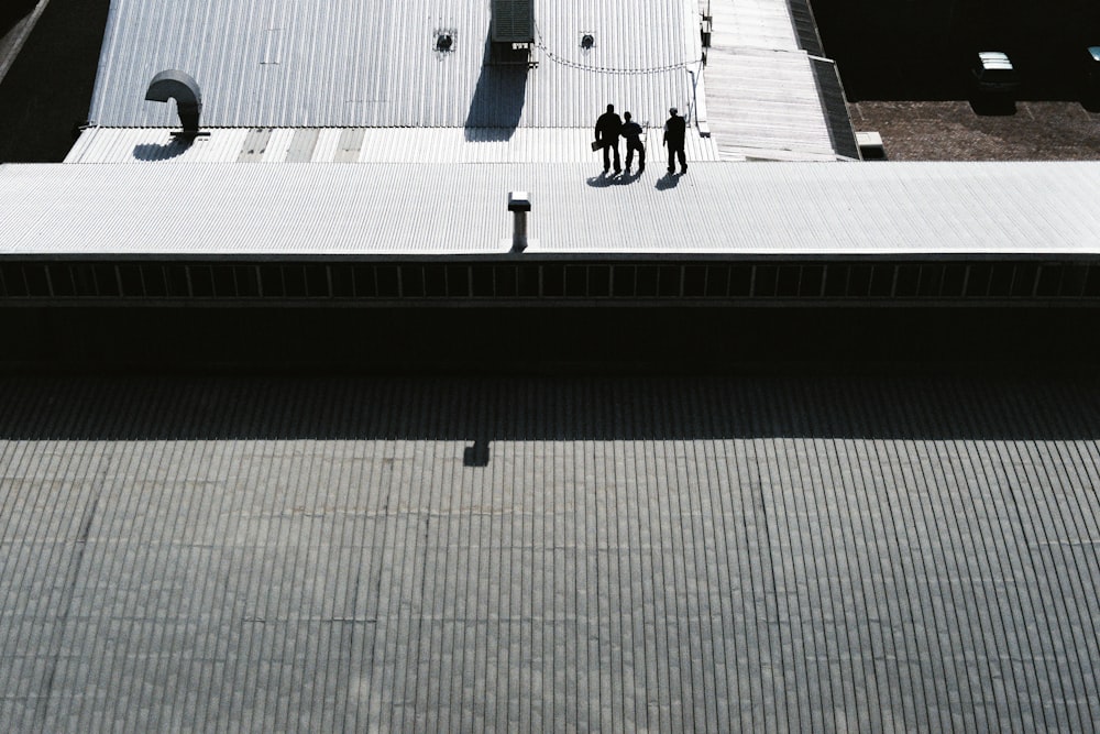 trois hommes debout sur un trottoir gris