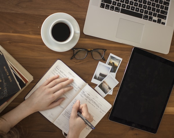 person holding ballpoint pen writing on notebook