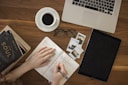 person holding ballpoint pen writing on notebook