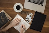 person holding ballpoint pen writing on notebook