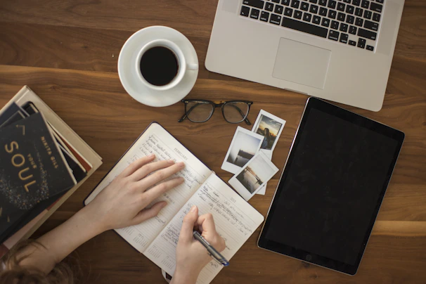 A graceful moment captured of a woman arranging her planner next to a cup of coffee in natural light.