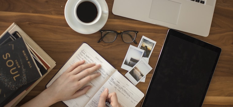 person holding ballpoint pen writing on notebook