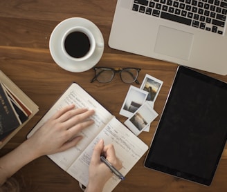 person holding ballpoint pen writing on notebook