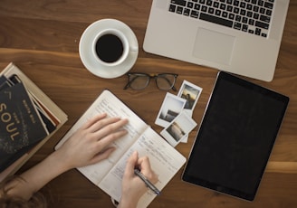 person holding ballpoint pen writing on notebook