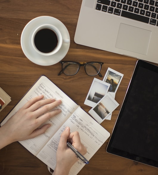 person holding ballpoint pen writing on notebook