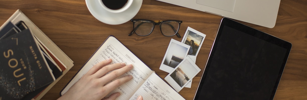 person holding ballpoint pen writing on notebook