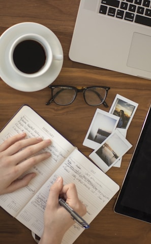 person holding ballpoint pen writing on notebook