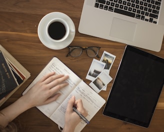 person holding ballpoint pen writing on notebook