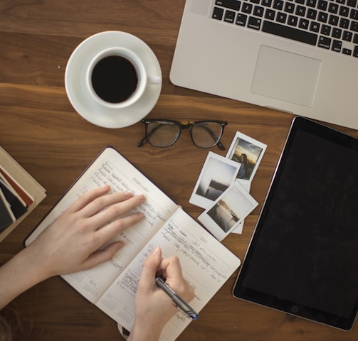 person holding ballpoint pen writing on notebook