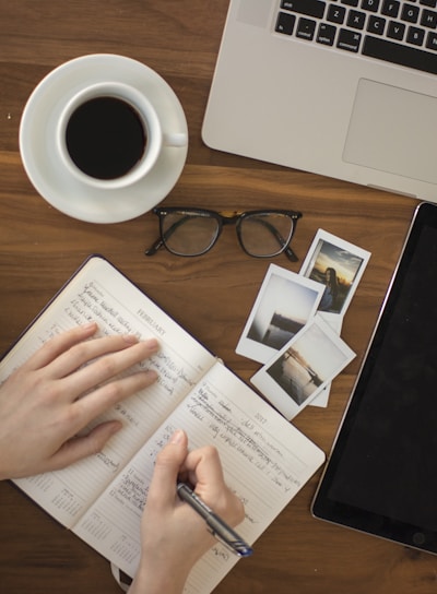 person holding ballpoint pen writing on notebook