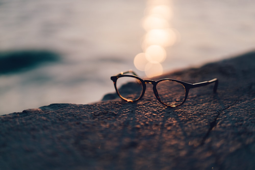 Photographie en gros plan de lunettes de soleil à verres transparents à monture noire près d’un plan d’eau