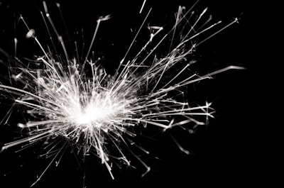 Sparks bursting outward in a dynamic and chaotic pattern against a dark background, creating a sense of movement and energy.