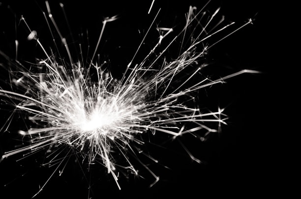 Sparks bursting outward in a dynamic and chaotic pattern against a dark background, creating a sense of movement and energy.