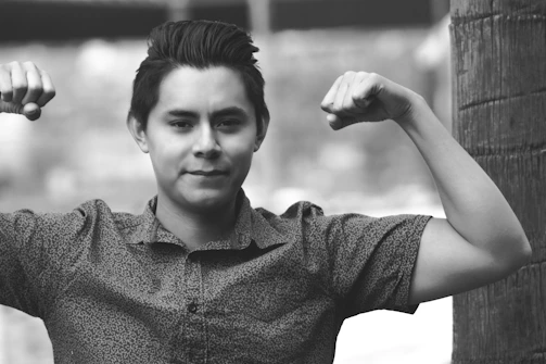 A confident man in business attire flexing his toned arms after a workout.
