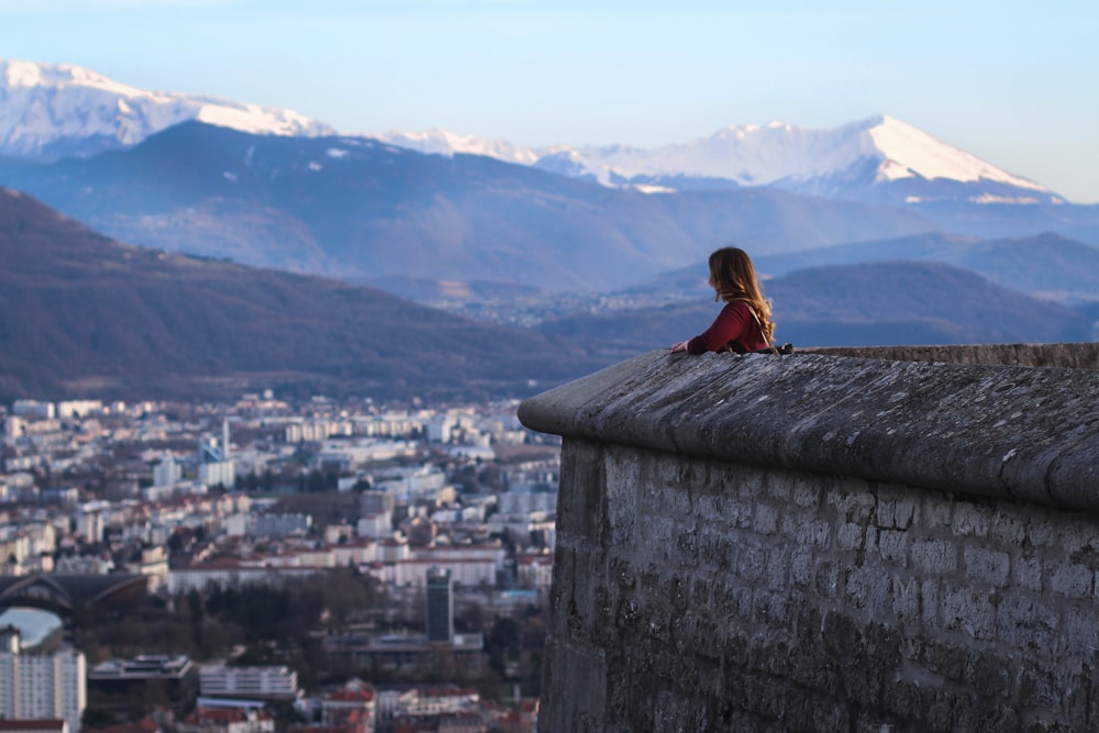 Femme debout près des immeubles de grande hauteur et des montagnes pendant la journée
