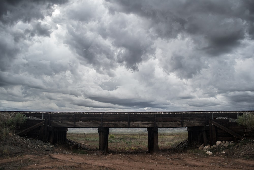 brown wooden bench under cloudy sky during daytime