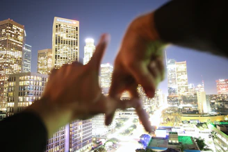 A close-up of hands shaking firmly against a backdrop of city skyscrapers, representing trust and collaboration.