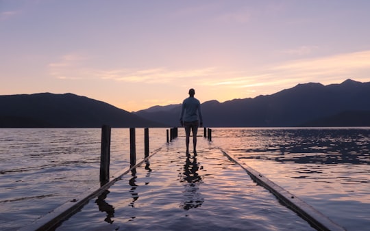 person standing on footboard filled with water in Lake Hauroko New Zealand