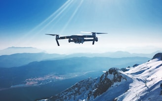 white quadcopter drone flying near snow mountain during daytime