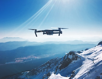 white quadcopter drone flying near snow mountain during daytime