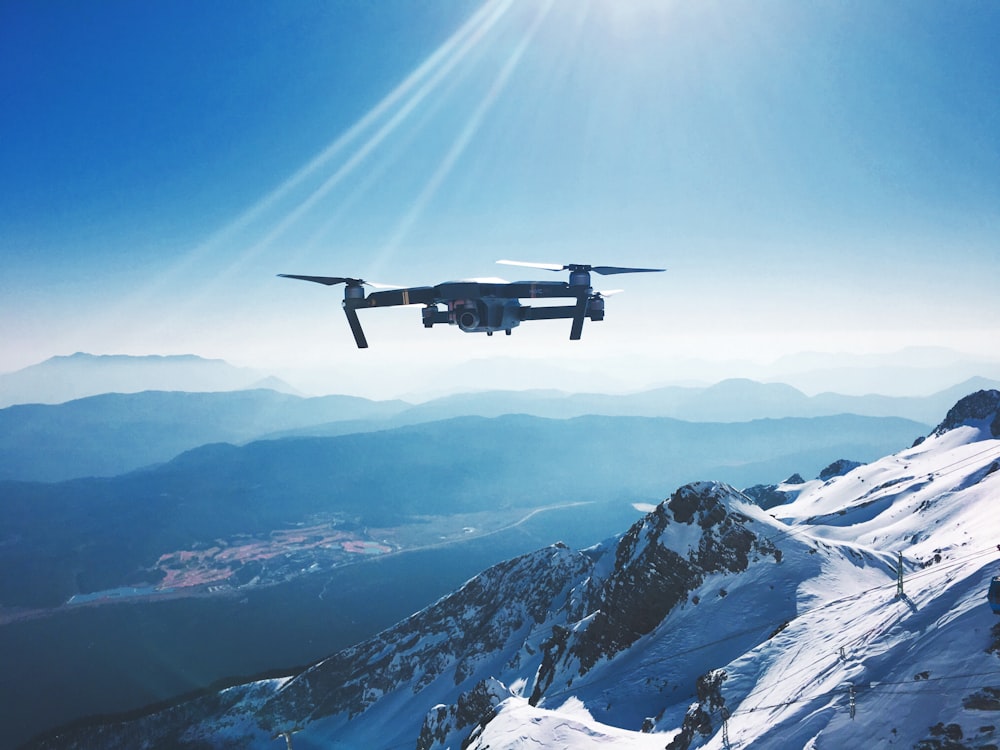 Weiße Quadrocopter-Drohne, die tagsüber in der Nähe von Snow Mountain fliegt