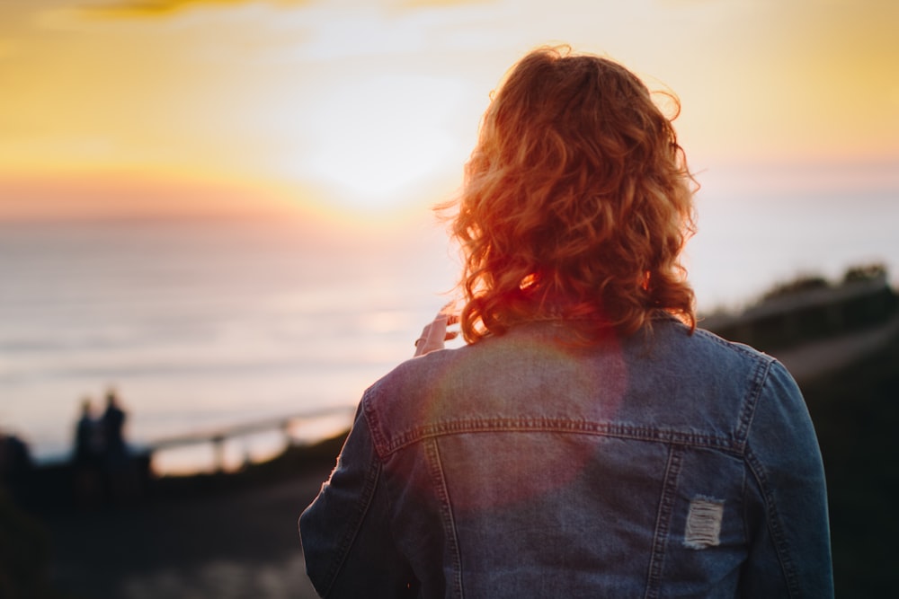 Mujer de pie frente al océano durante la puesta del sol