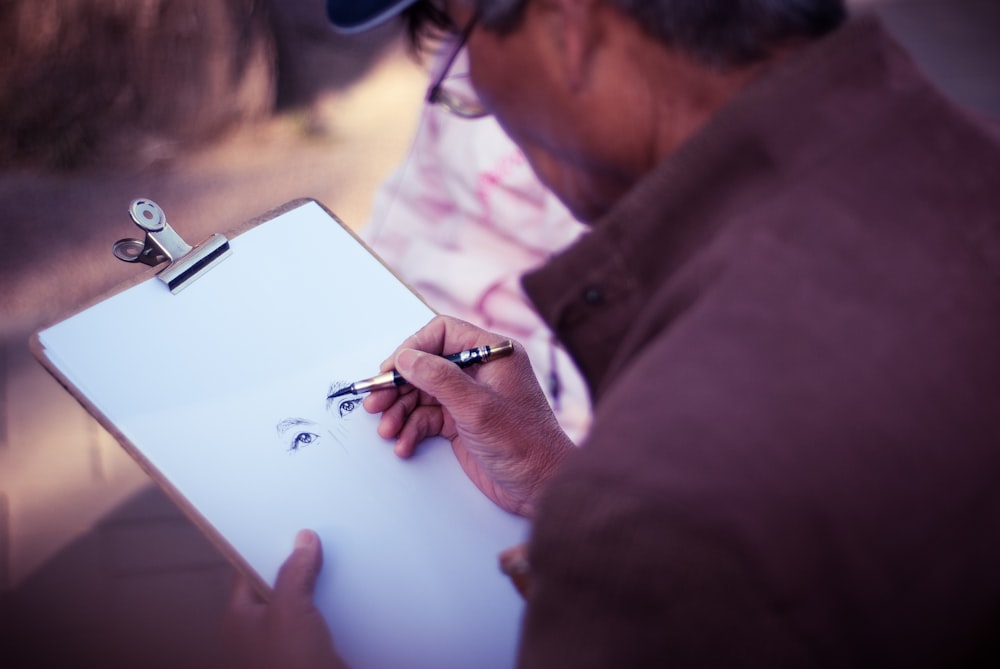 Mann skizziert Gesicht auf weißem Druckerpapier
