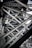 Intricate steel beams and trusses form a complex lattice structure, showcasing industrial design and engineering. The interlocking metal components create geometric patterns with rivets visible throughout the structure.