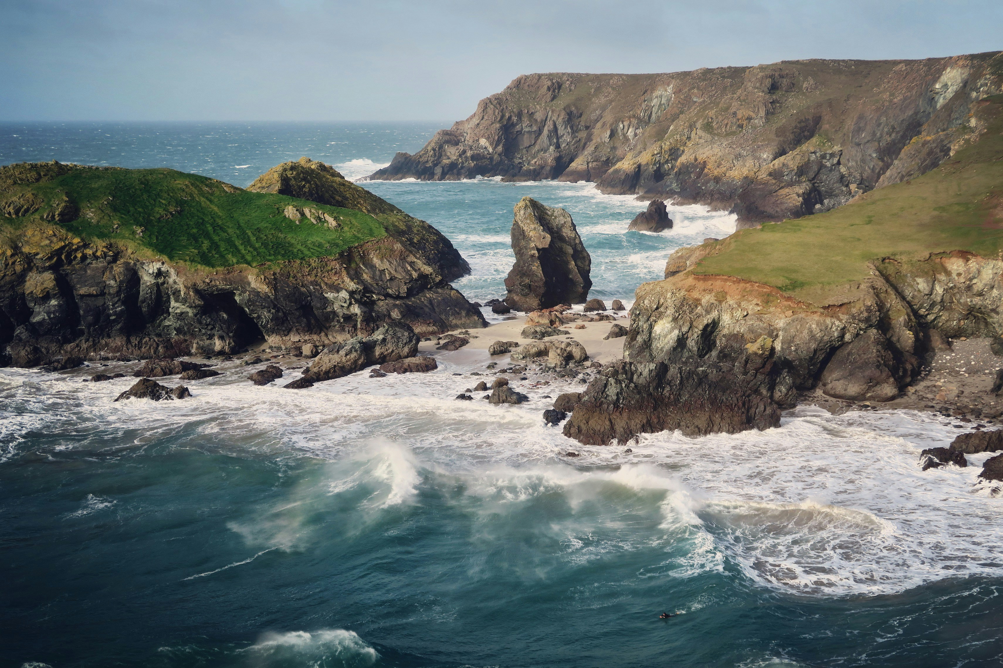 photo of sea waves and boulders, The Day of Storm Doris and I decided to brave Kyance Cove. Probably not the cleverest move given the forecast was giving 70mph gusts. It seemed I wasn’t the only insane person and a lone Surfer was making the most of the big Waves. This place was stunning.