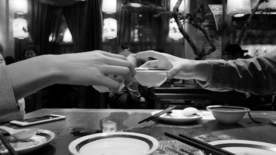 A smiling couple enjoying a vibrant Asian fusion meal at a dimly lit table with dark charcoal accents.