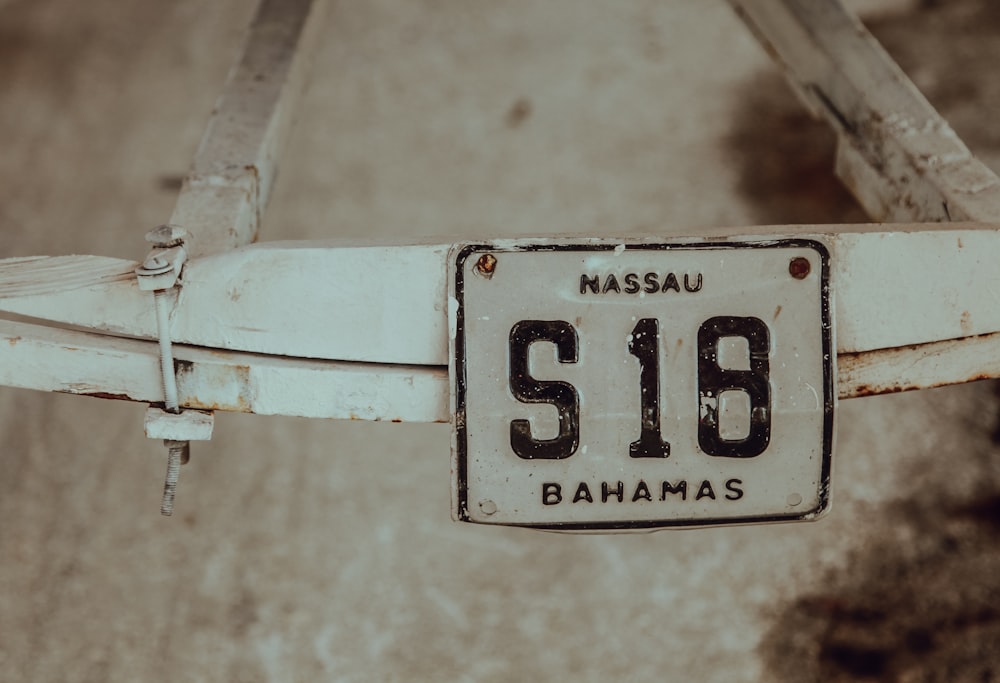 fotografía de enfoque superficial de la matrícula blanca Massau S18 Bahamas montada en un marco de acero blanco