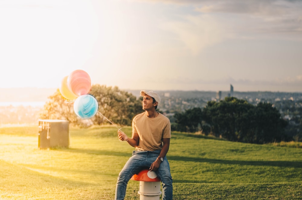 man sitting while holding balloons