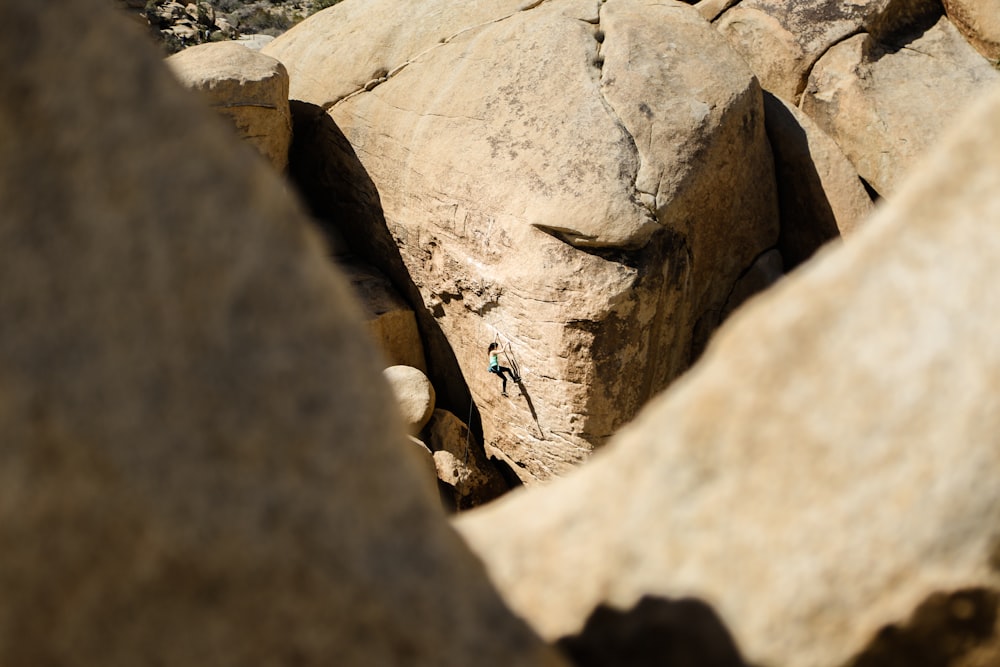 femme grimpant sur un rocher brun pendant la journée