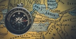 round gray framed compass on brown map