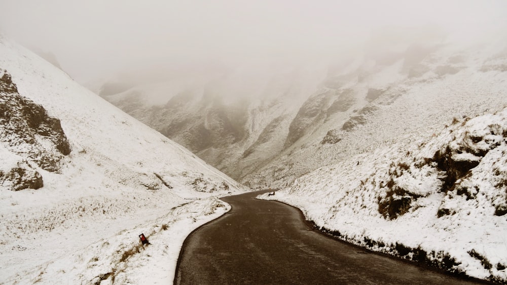 estrada de asfalto cercada por campo coberto de neve durante o dia