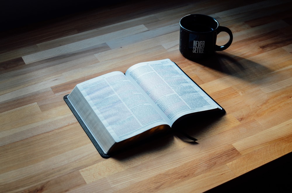 opened book beside black ceramic mug