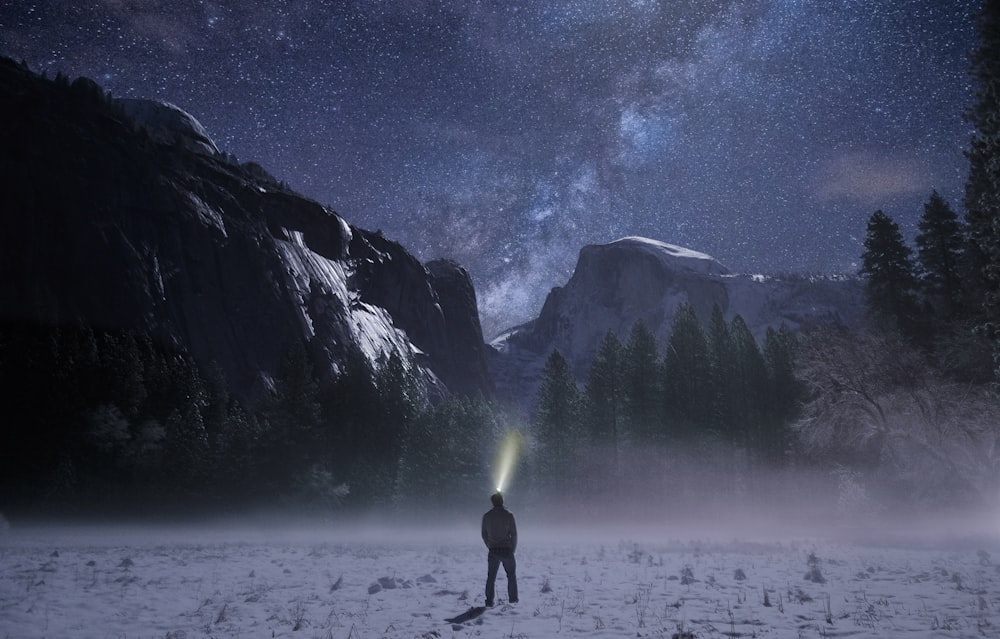 Persona con linterna frontal mirando hacia la montaña nevada
