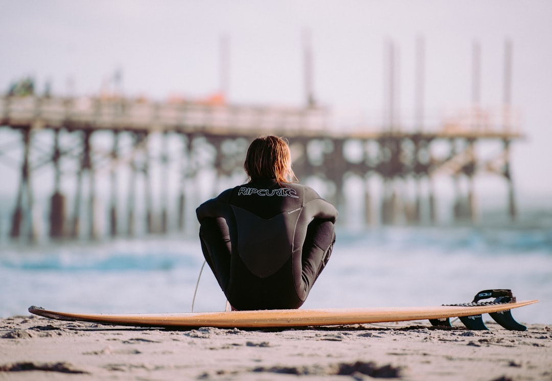 person sitting on gray sand near body of water, The Unsplash Community Team were awake before the sun rose and drive to Coca Beach to watch the sun rise.<p></figure>Added bonus - surfers galore!