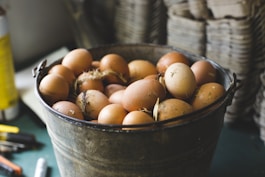 Close-up of fresh organic eggs in a rustic basket on a wooden table.