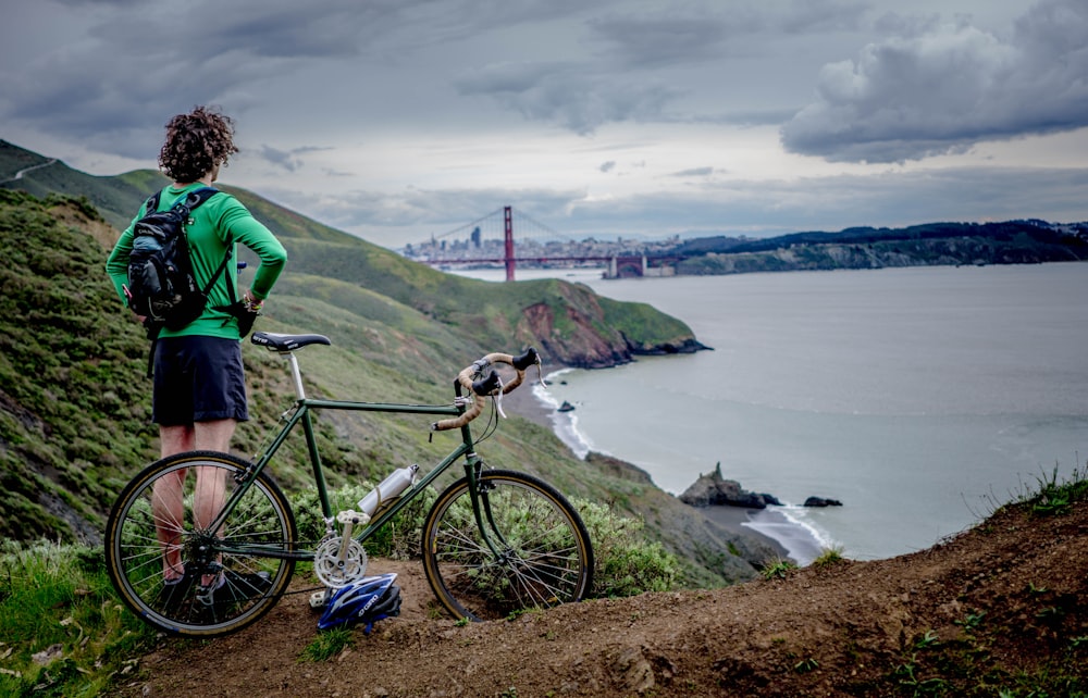 man standing beside bike on top of mountain