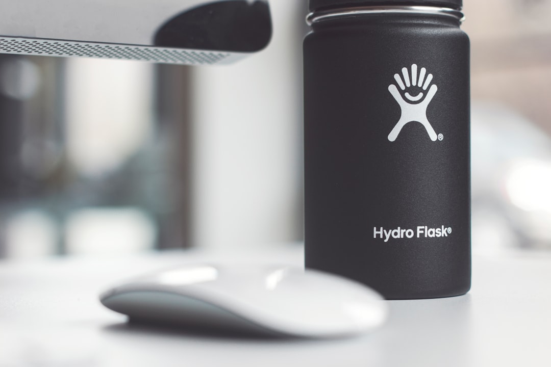 white Apple Magic Mouse beside Hydro Flask jar