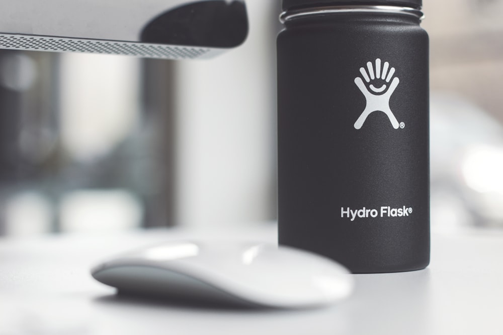 white Apple Magic Mouse beside Hydro Flask jar