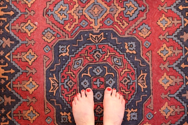 Vibrant red pedicure with glossy finish on feet resting on a plush towel.