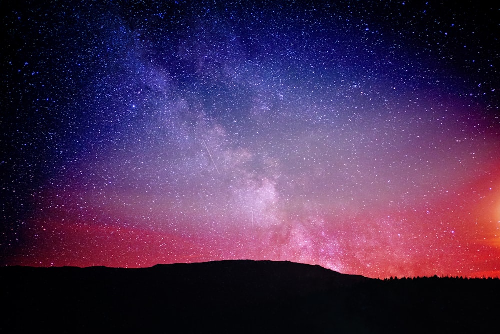 a person standing on a hill looking up at the night sky